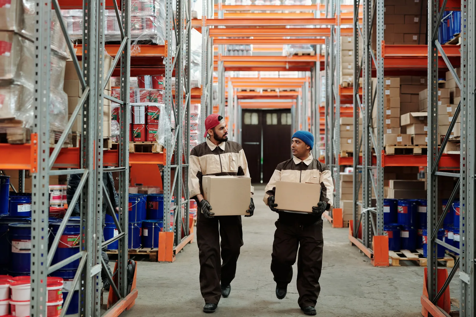 Two workers carrying boxes in a warehouse aisle, engaged in logistics. Storage systems planning: six core priorities