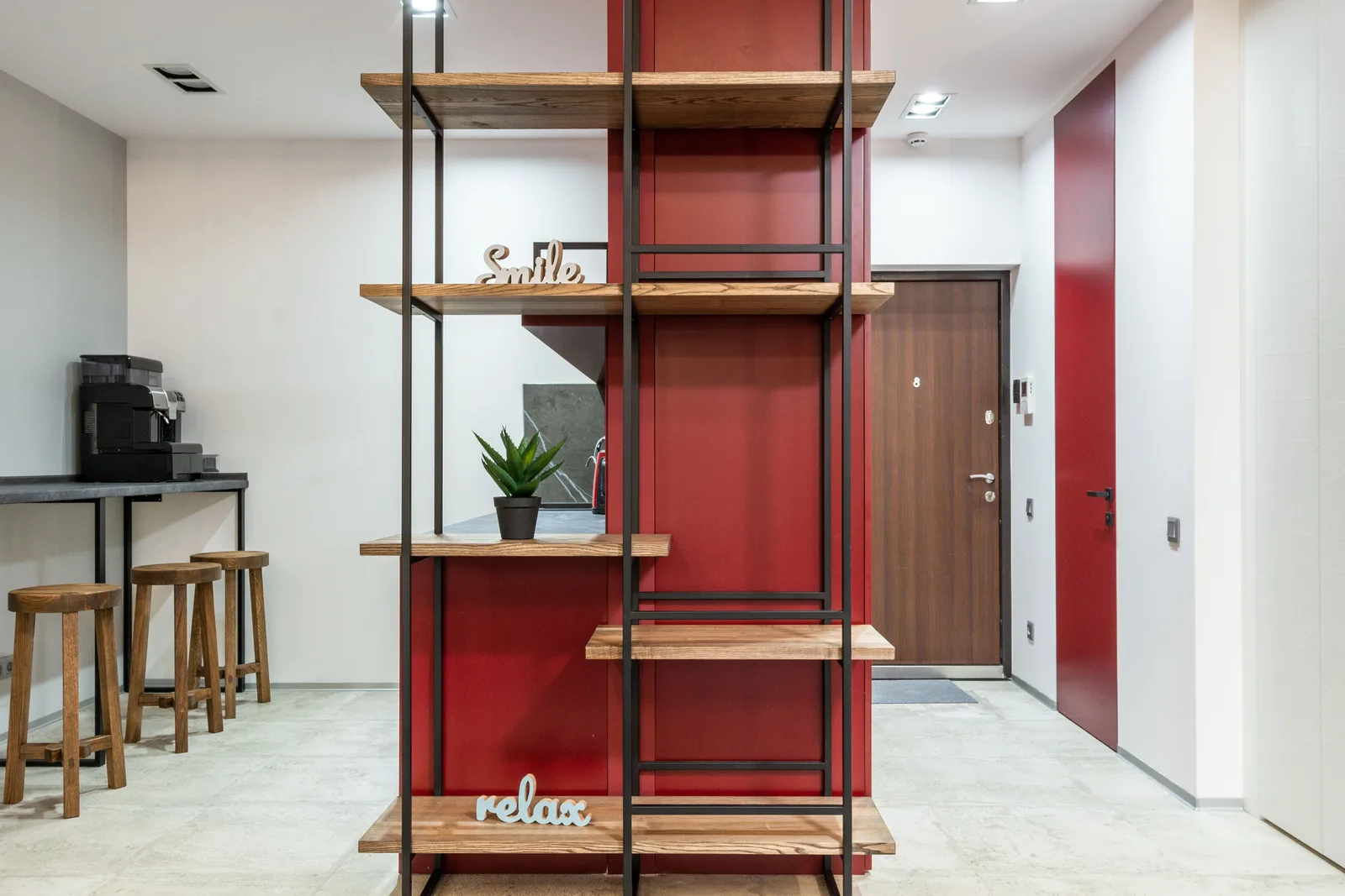 Interior of modern organization with wooden shelves with words smile and relax near potted cactus next to table with chairs. Professional organizers: sort first, install second