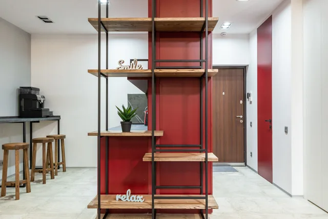 Interior of modern organization with wooden shelves with words smile and relax near potted cactus next to table with chairs. Professional organizers: sort first, install second