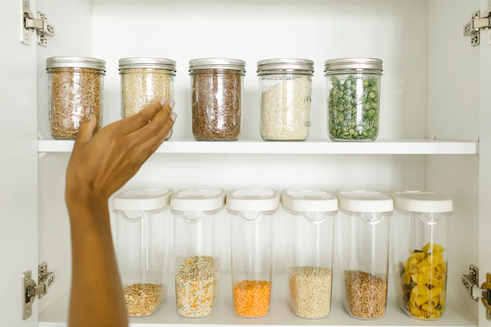 A neat pantry shelf showing various grains stored in labeled glass and plastic containers, promoting kitchen organization. Inside a typical pantry organization project, stage by stage