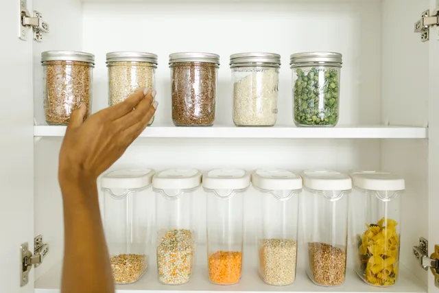 A neat pantry shelf showing various grains stored in labeled glass and plastic containers, promoting kitchen organization. Inside a typical pantry organization project, stage by stage