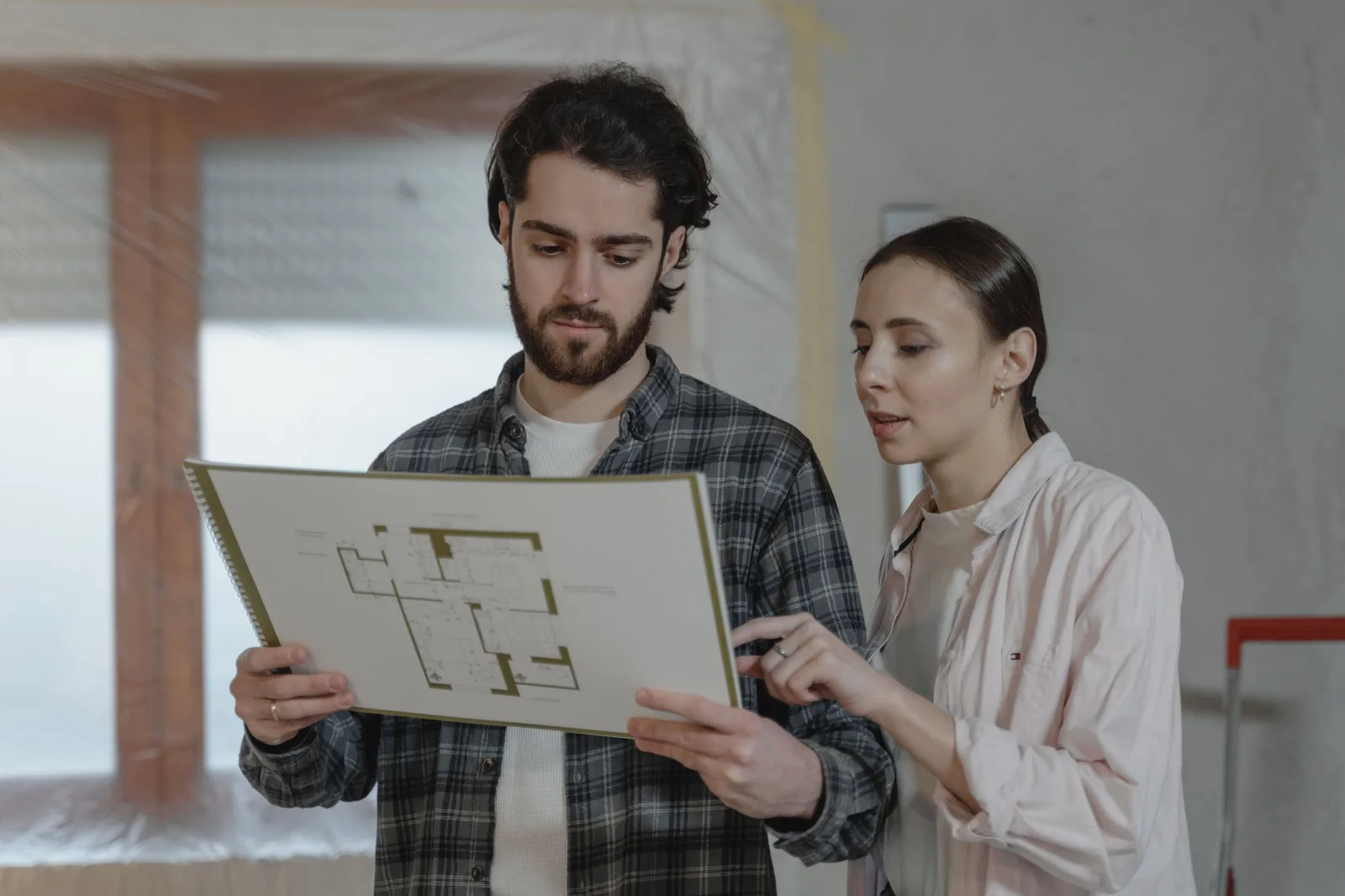 A man and woman examining a floor plan for home improvement indoors. Questions to settle with a home organization contractor